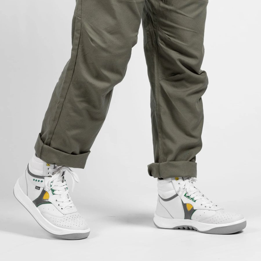 White high-top sneakers with green and yellow accents worn with cuffed olive pants