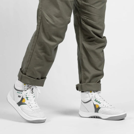 White high-top sneakers with green and yellow accents worn with cuffed olive pants