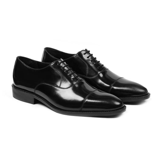Polished black leather Oxford dress shoes with closed lacing and cap toe on white background