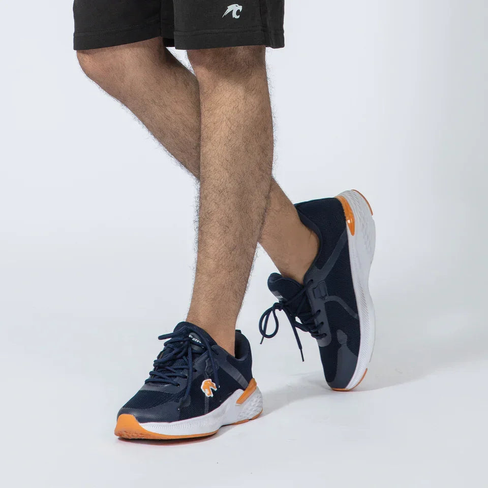 Man wearing navy blue athletic sneakers with orange accents on a white background