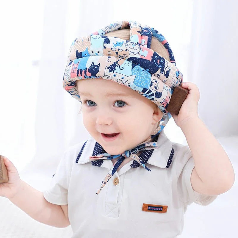 Cute baby wearing a colorful padded safety helmet with animal prints, smiling indoors