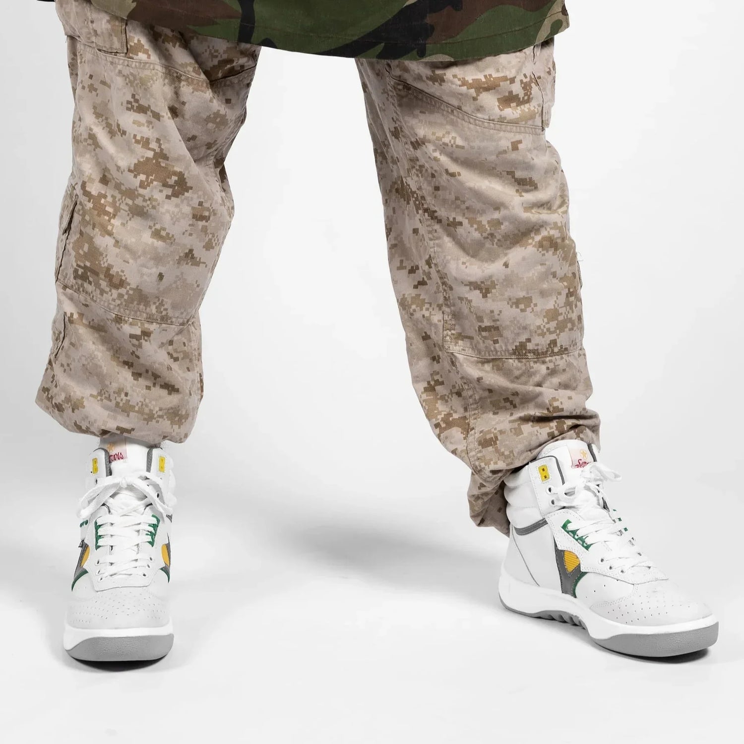 White high top sneakers with green and yellow accents worn with camouflage pants