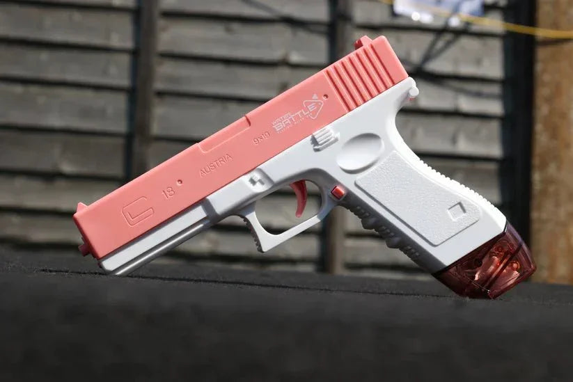 Pink and white toy pistol with transparent magazine on a black surface outdoors